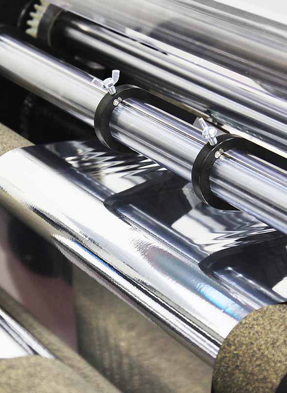 Foil printing machine rollers applying metallic foil to material, illustrating how the foil printing process works