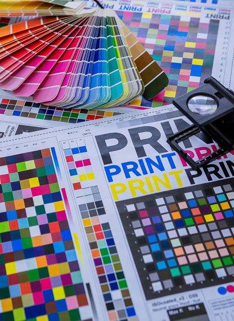 Close up of colour swatches, print test sheets and a magnifier, showing detailed proof checking and colour accuracy in printing
