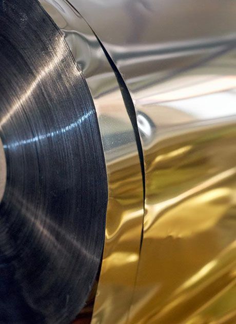 Close-up of metallic foil reels in a printing press, illustrating the materials used to create premium foil printed finishes.
