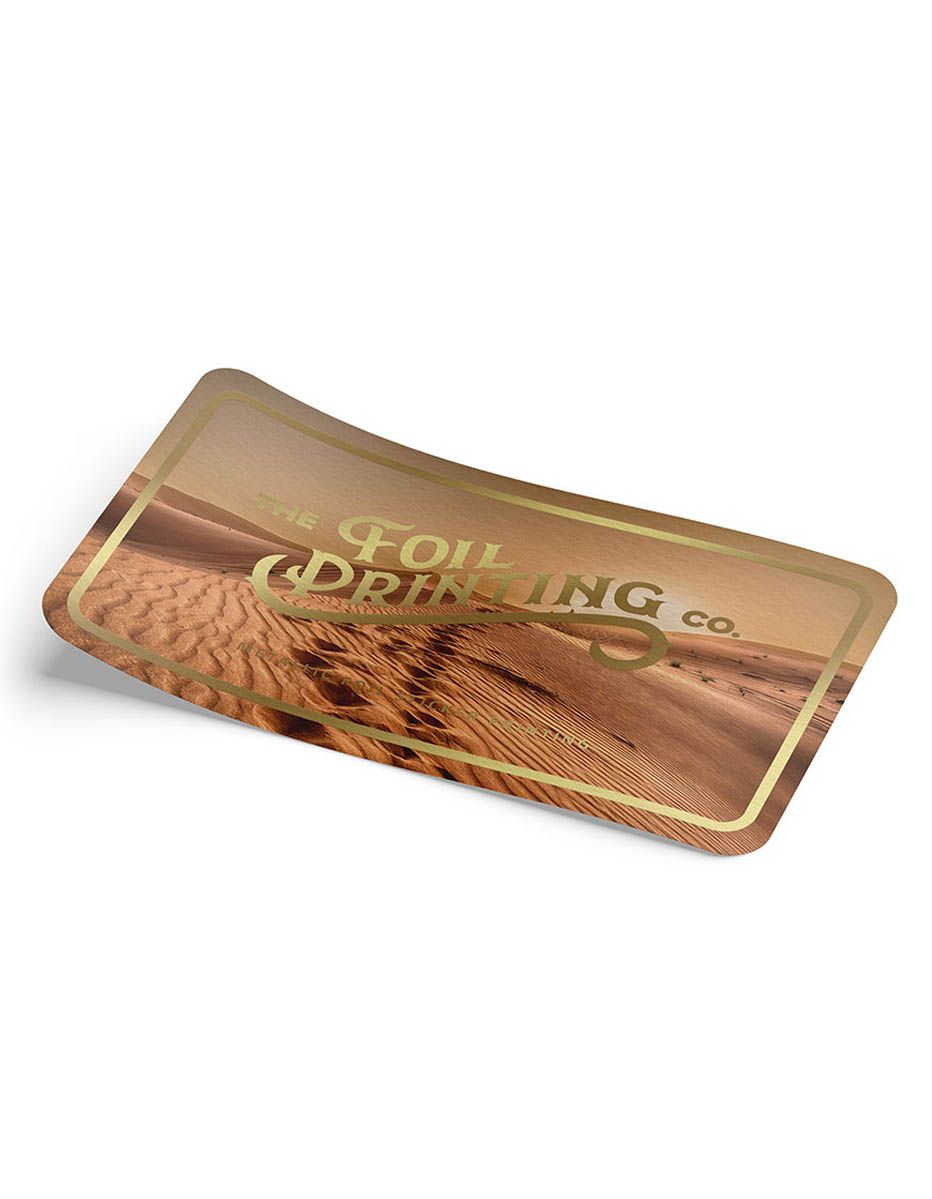 Foil sticker printing sample with metallic gold foil logo on a curved rectangular sticker with glossy finish