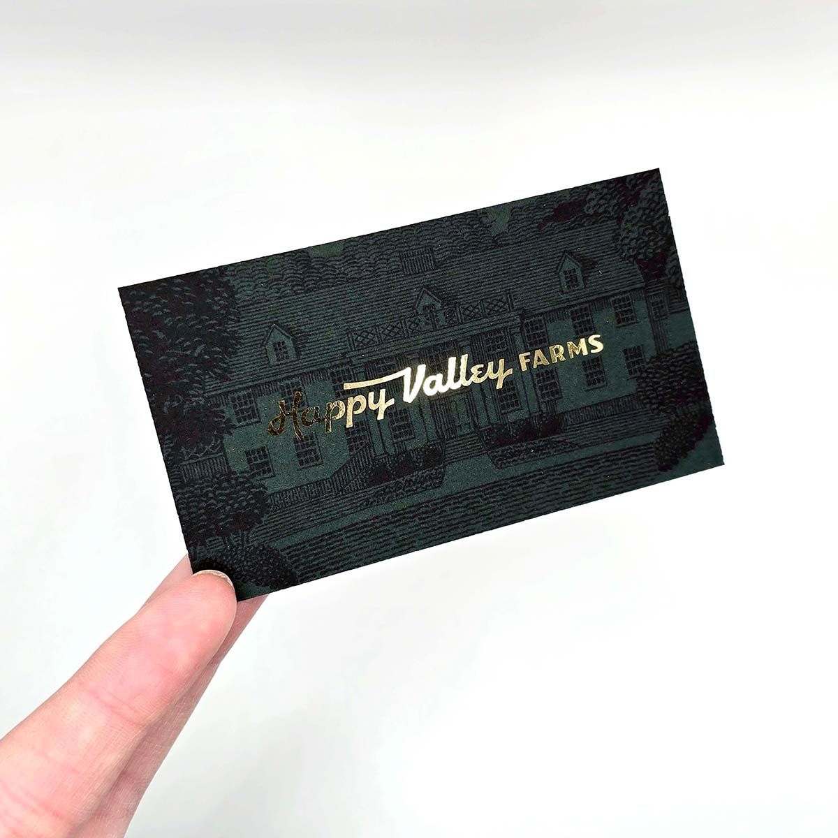 Metallic gold Forest Colour Core Happy Valley Farms business card with dark green heritage-style mansion illustration, gold foil logo and thick coloured card stock.