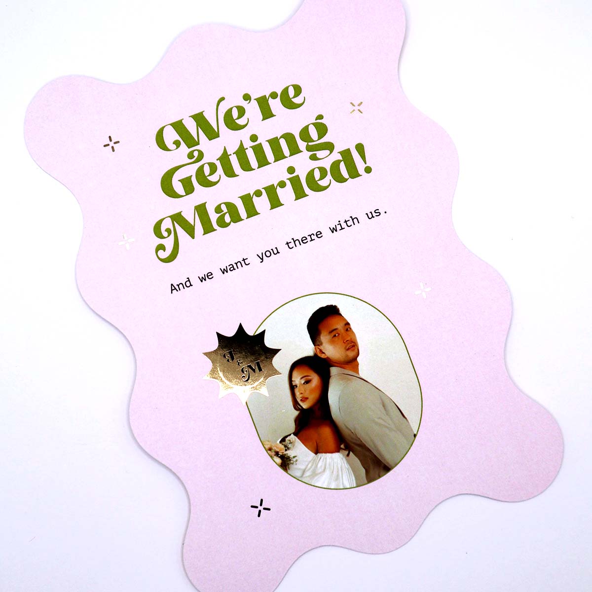 Pastel pink wedding invitation flyer with a die-cut edge design, featuring metallic gold foil name logo and a photo of the couple