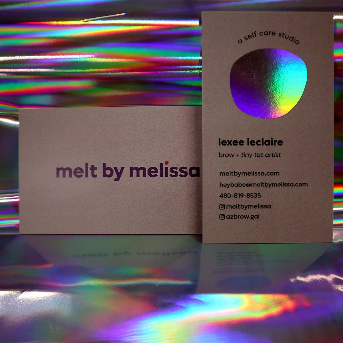 Set of modern business cards displayed against a shimmering holographic background printed on silk paper with a double sided design